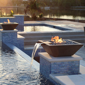 The Lombardo-P fire and water combination bowl installed on pedestals around a pool by a lake.