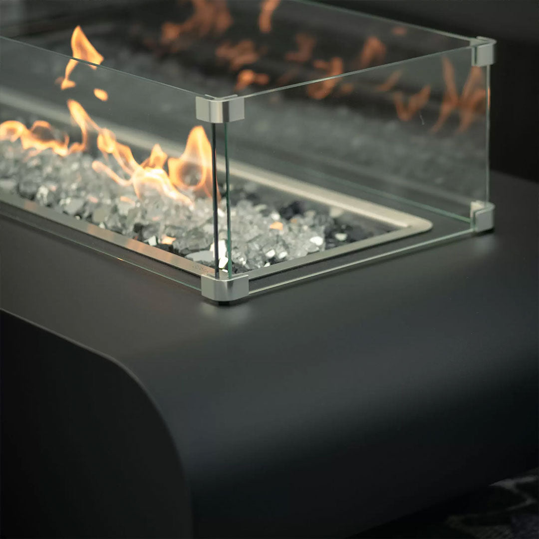 A close up, angle shot of a fire table with a glass wind guard.