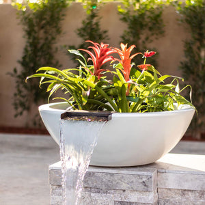 The Outdoor Plus Sedona water bowl with a planter with bright, tropical flowers pouring water out into a pool that is outside the shot.